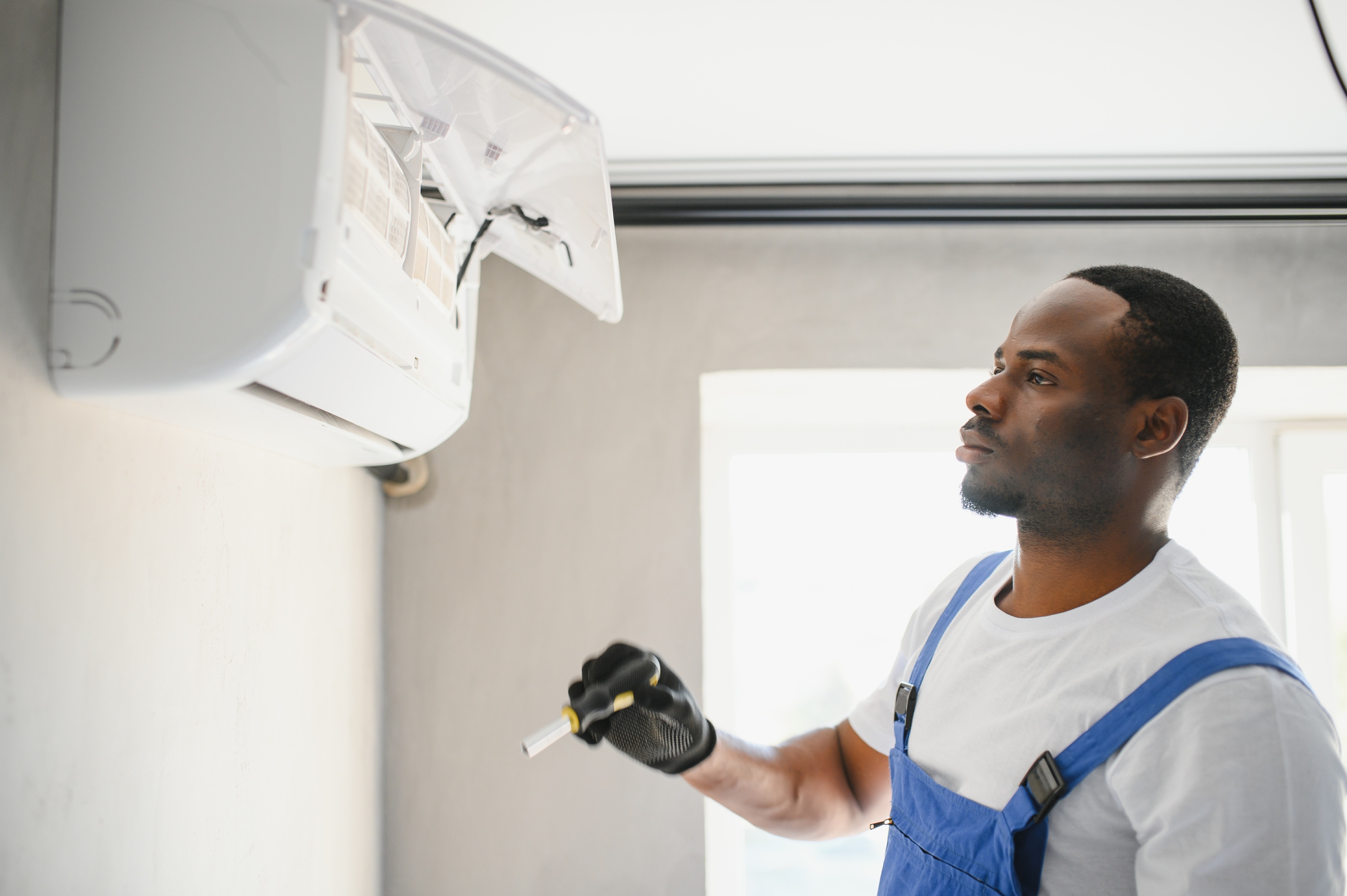 Technician inspecting an air conditioning unit, emphasizing the role of energy-efficient repairs in improving performance and reducing long-term energy costs. Technician inspecting an air conditioning unit, emphasizing the role of energy-efficient repairs in improving performance and reducing long-term energy costs.