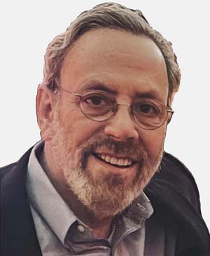 Potrait Image of Roy Cranman smiling in a black suit and grey shirt with glasses smling