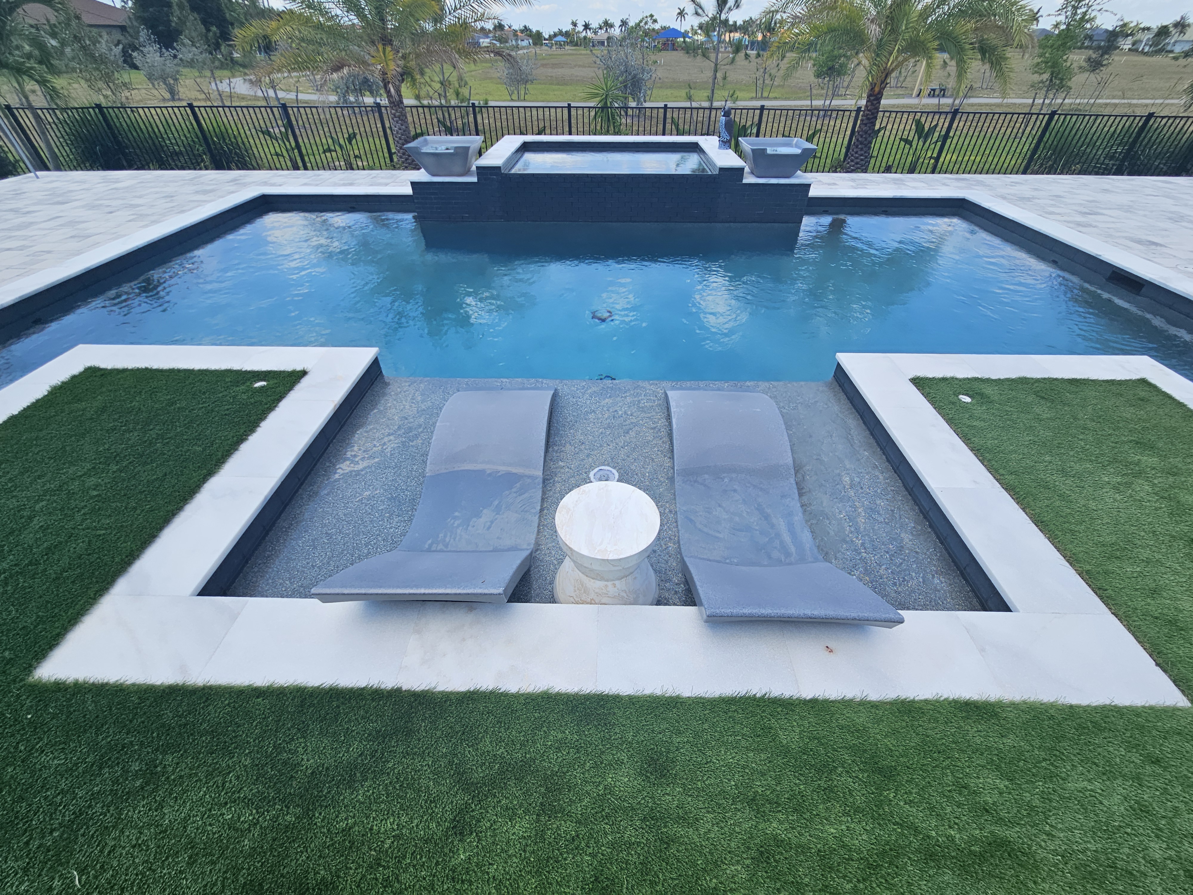 Custom inground concrete pool with integrated sun ledge by Design Concepts in Lee County, Florida