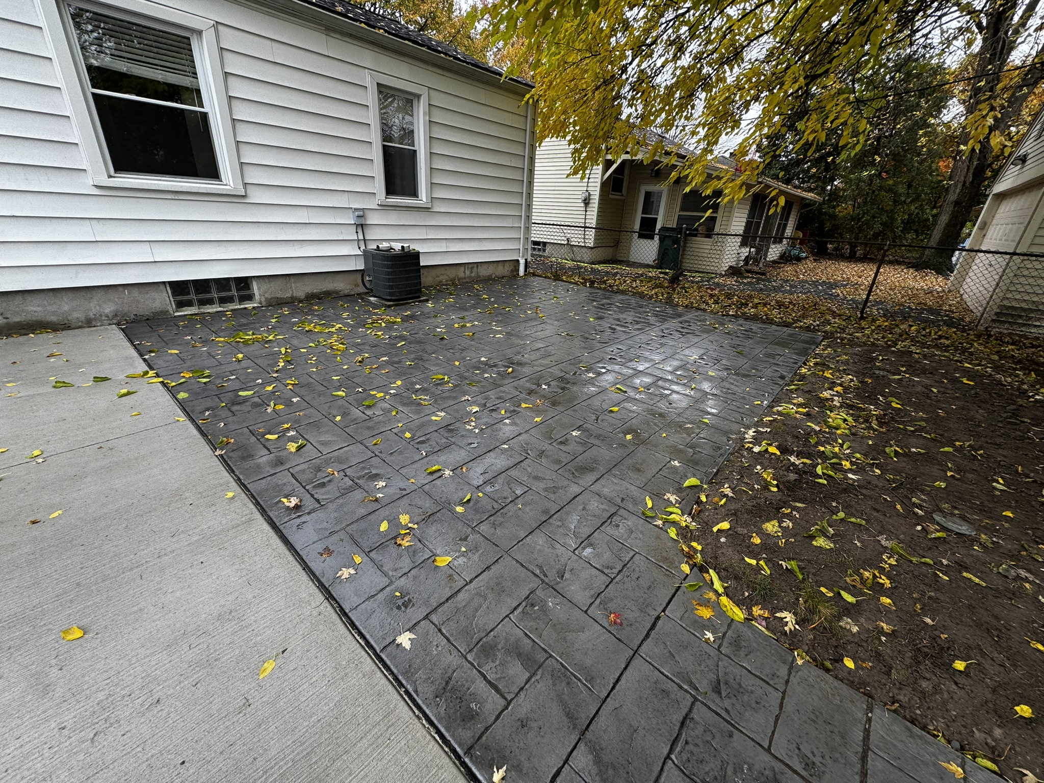 Gray stamped concrete walkway with decorative texture beside a home