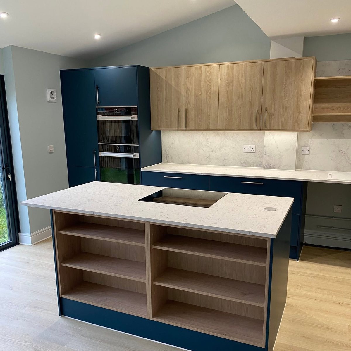 Kitchen island with open oak shelving and flush induction hob