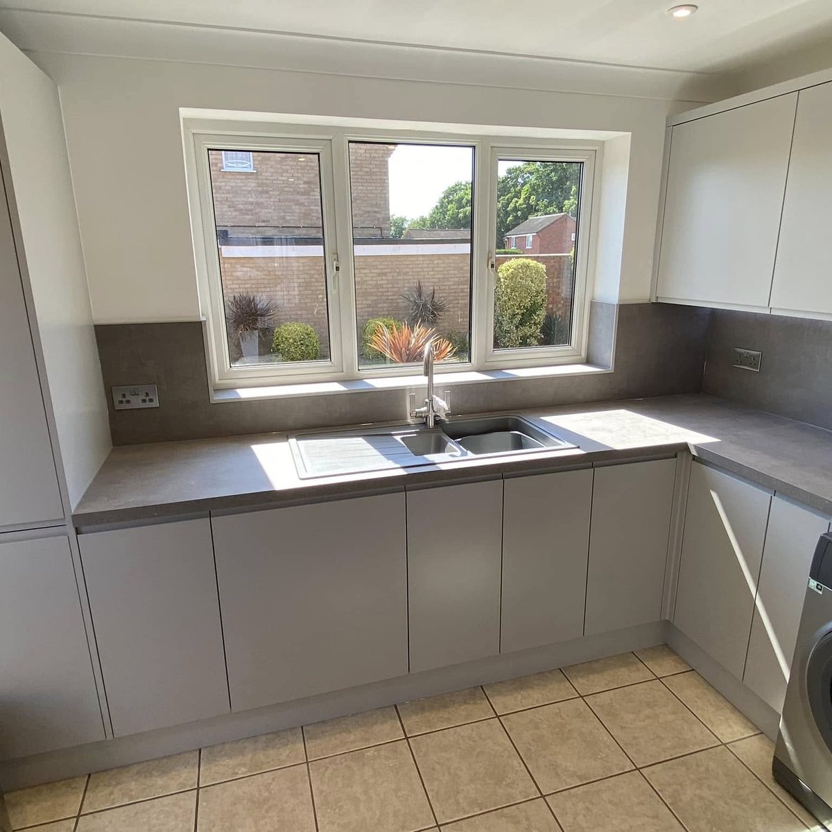 U-shaped grey handleless kitchen with sink beneath the window