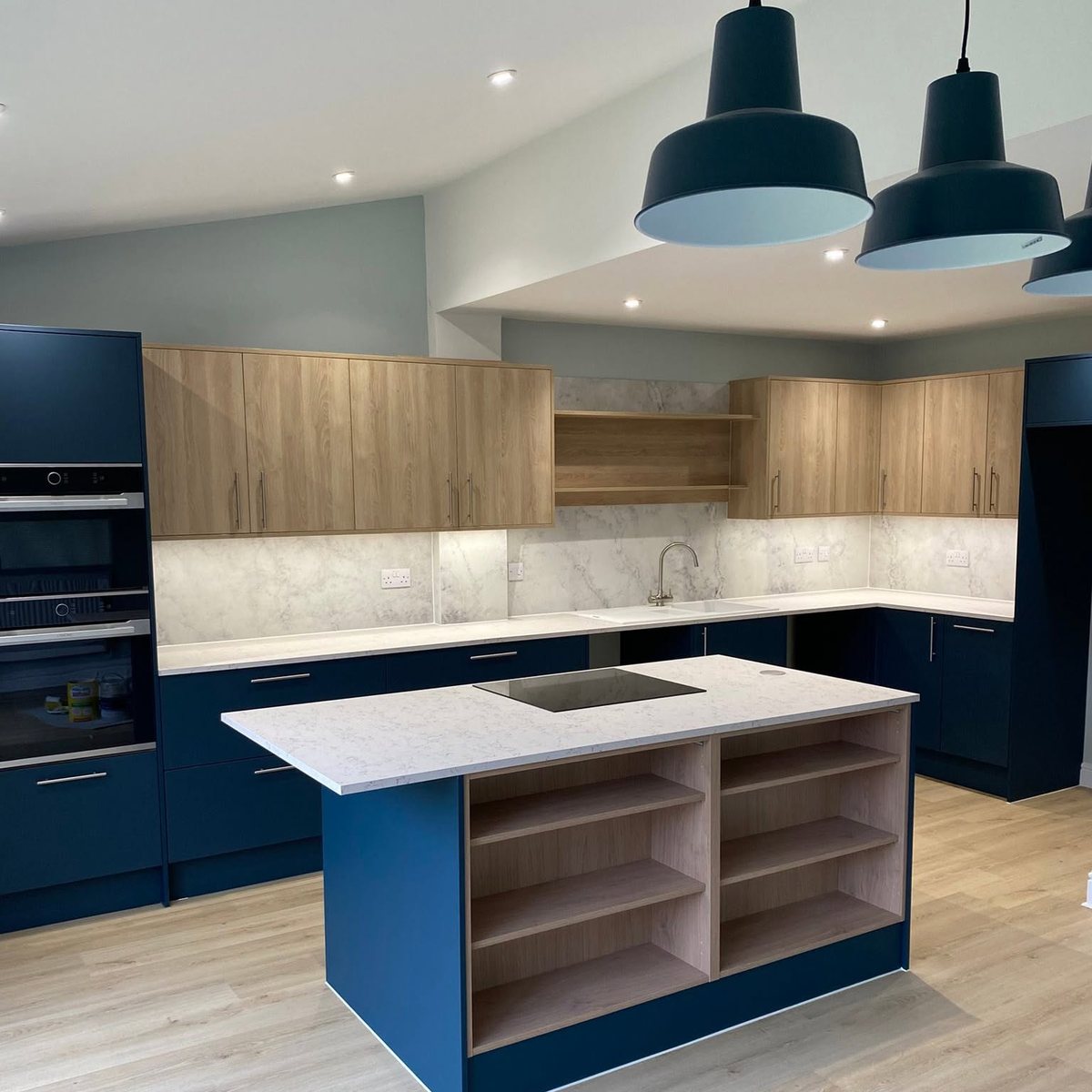 Navy and oak kitchen with quartz topped island and pendant lights