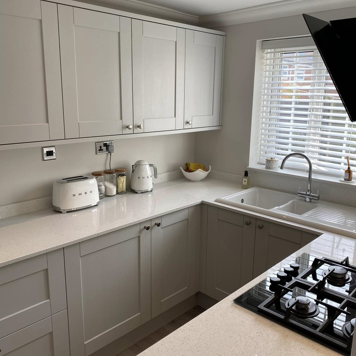 Light grey shaker kitchen with sink under the window and quartz worktops