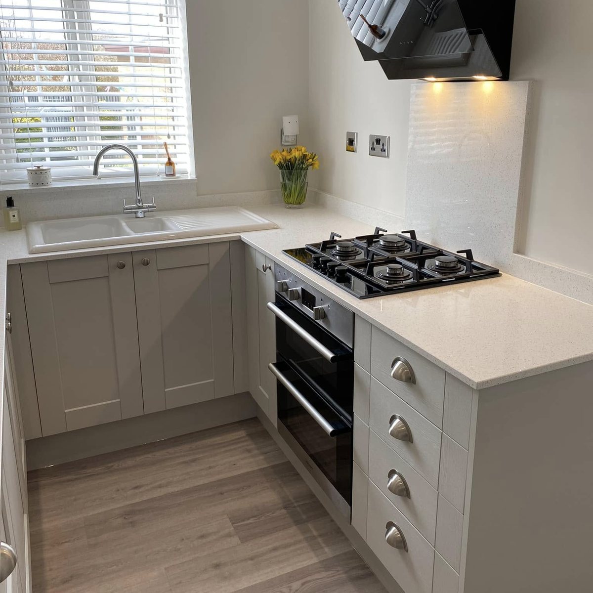 Light grey shaker kitchen with gas hob, angled extractor and quartz worktops