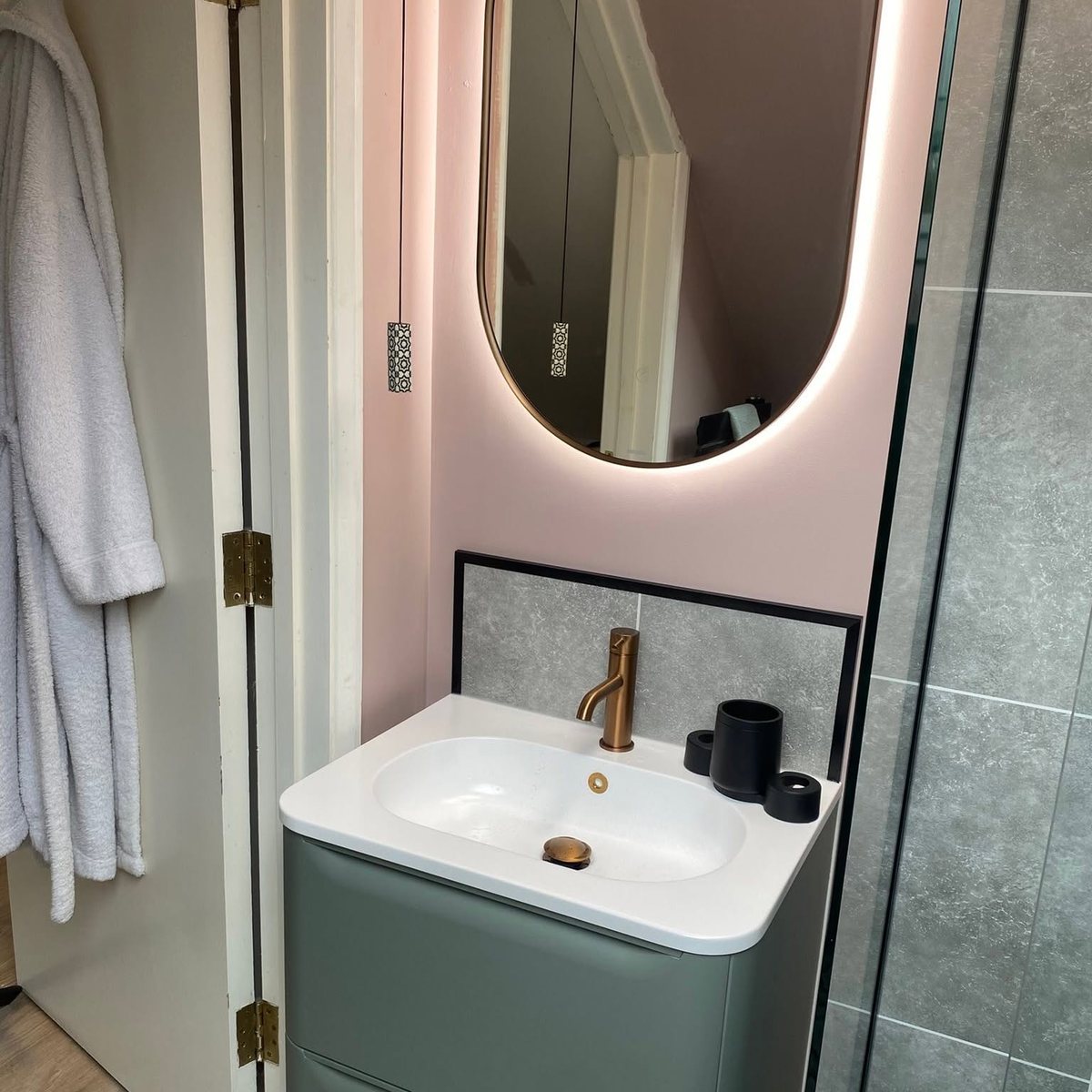 En-suite with backlit mirror, sage vanity unit and copper tap