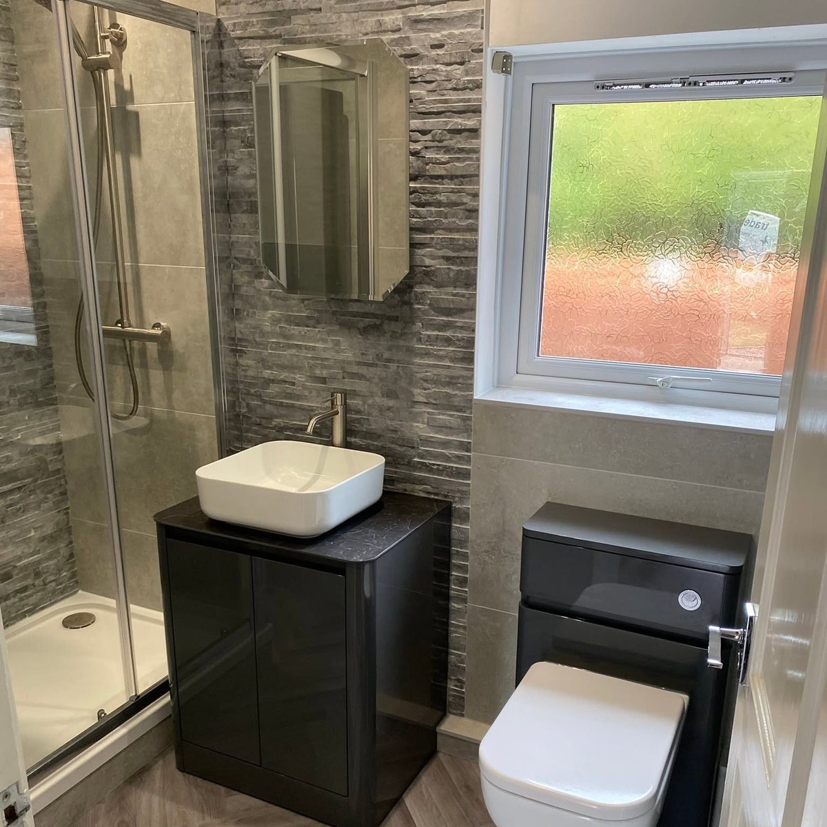 Shower room with slate effect feature wall, vessel basin and black vanity