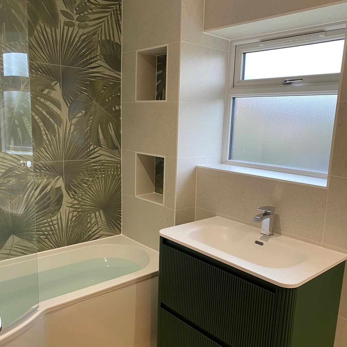 Bathroom with palm leaf feature tiles, P-shaped bath and green fluted vanity unit
