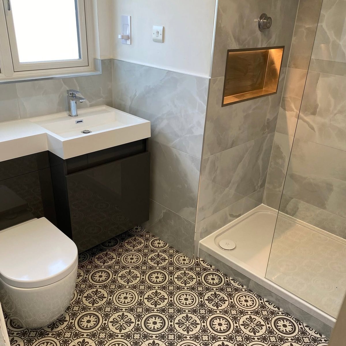 Shower room with illuminated tiled niche and patterned floor tiles