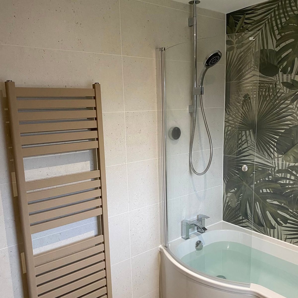 Shower bath with palm feature wall and bronze towel radiator