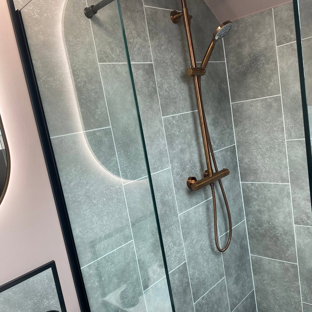 Walk-in shower with brushed copper shower set and grey stone effect tiles