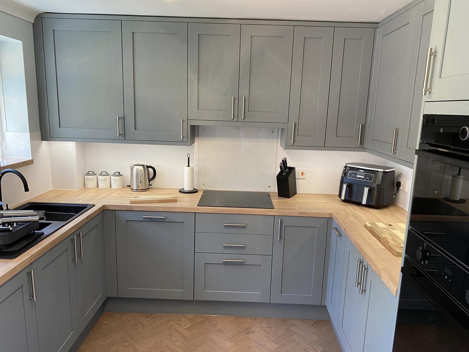 Sage shaker kitchen with oak worktops and herringbone floor, fitted in Suffolk by tradeMark Kitchens
