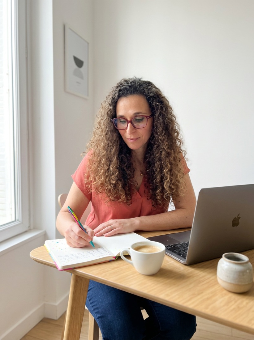 Flavie Berleand writing up an audit by hand, laptop open beside her