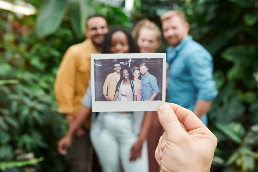 A sharp instant photo held in front of the same group, blurred