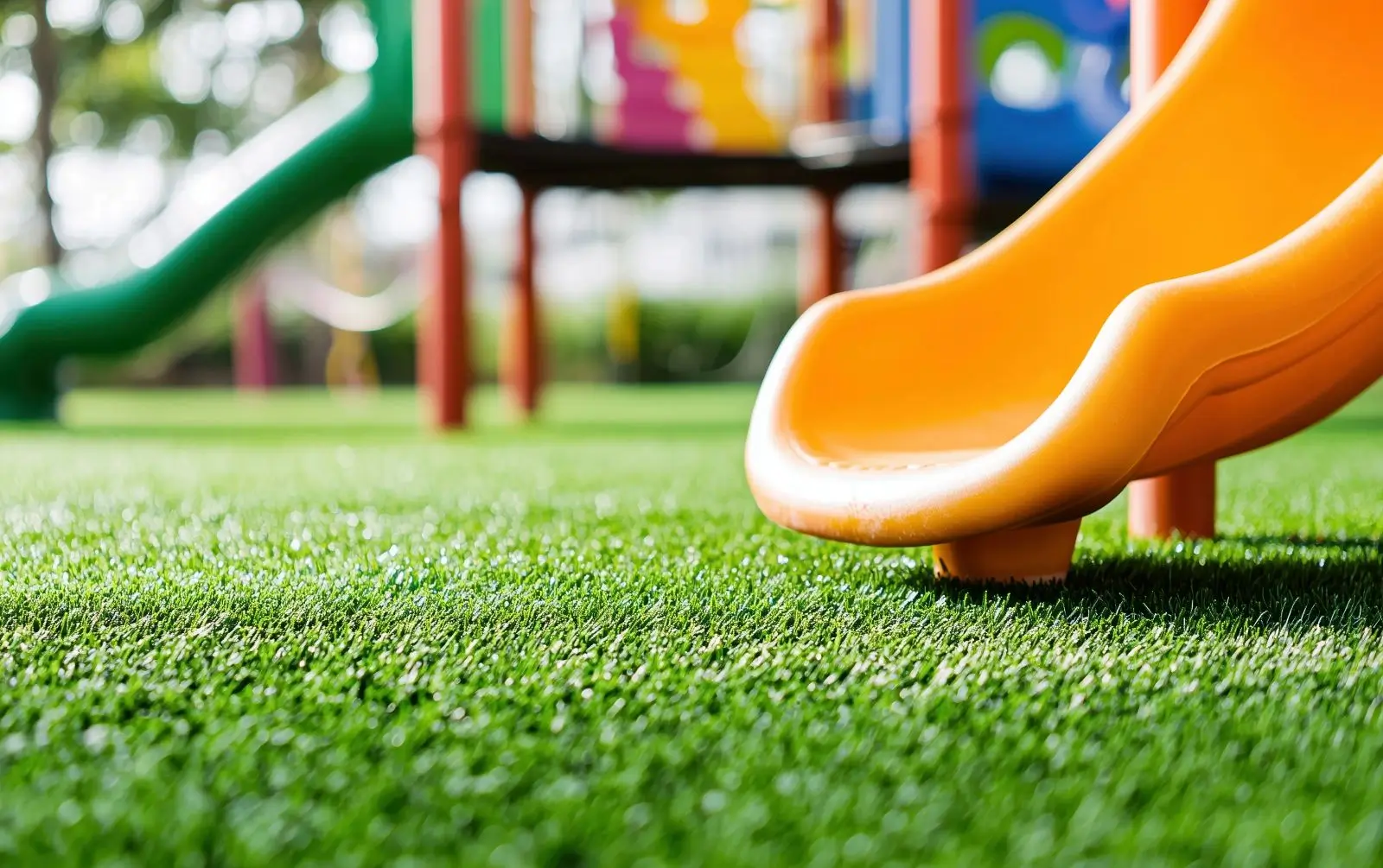 Continuous playground turf around in-ground trampoline connecting play equipment and gathering space
