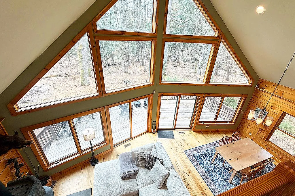 Great room with cathedral wall of windows and forest views