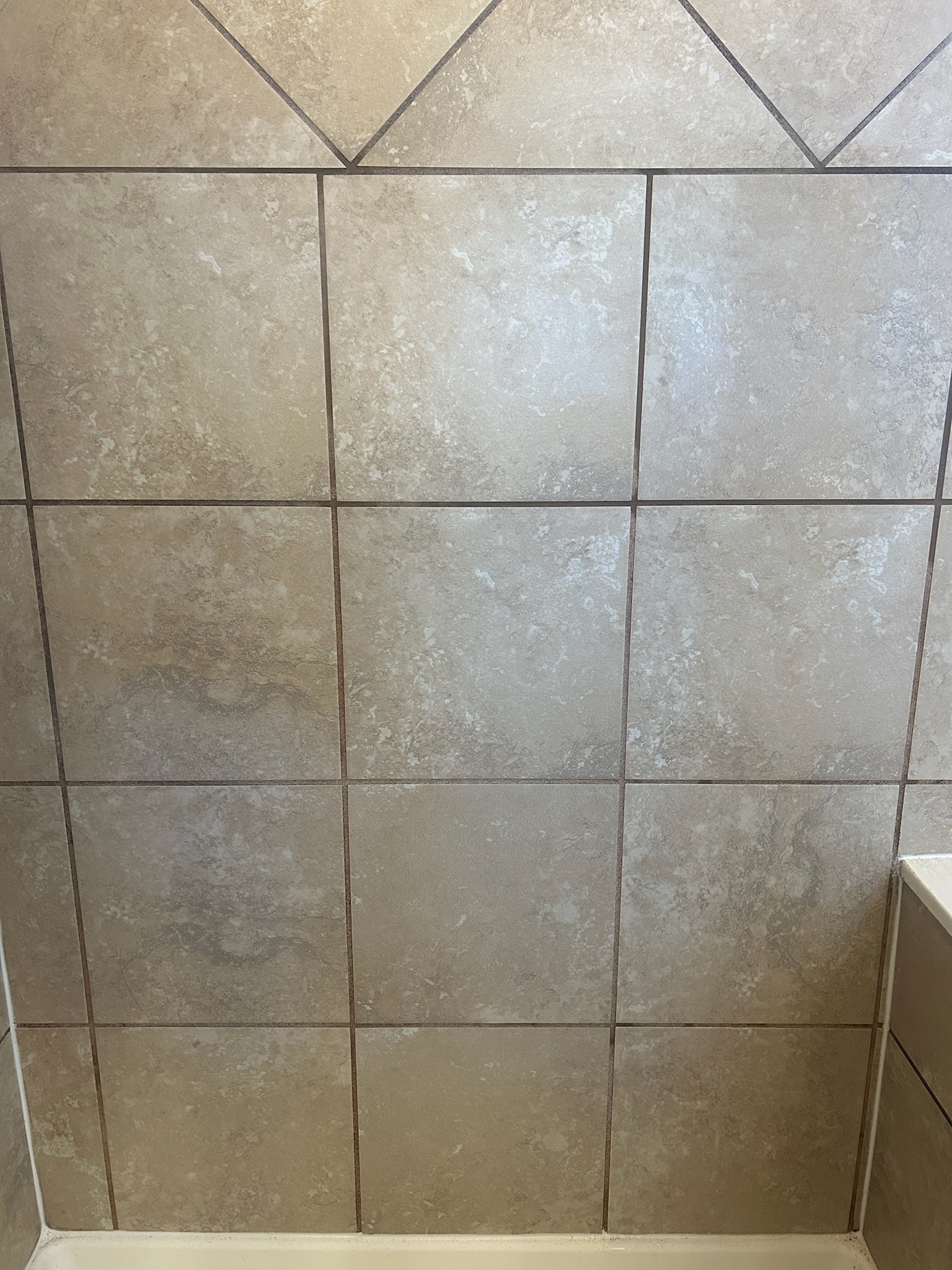 Bathtub tile wall with discolored failing grout