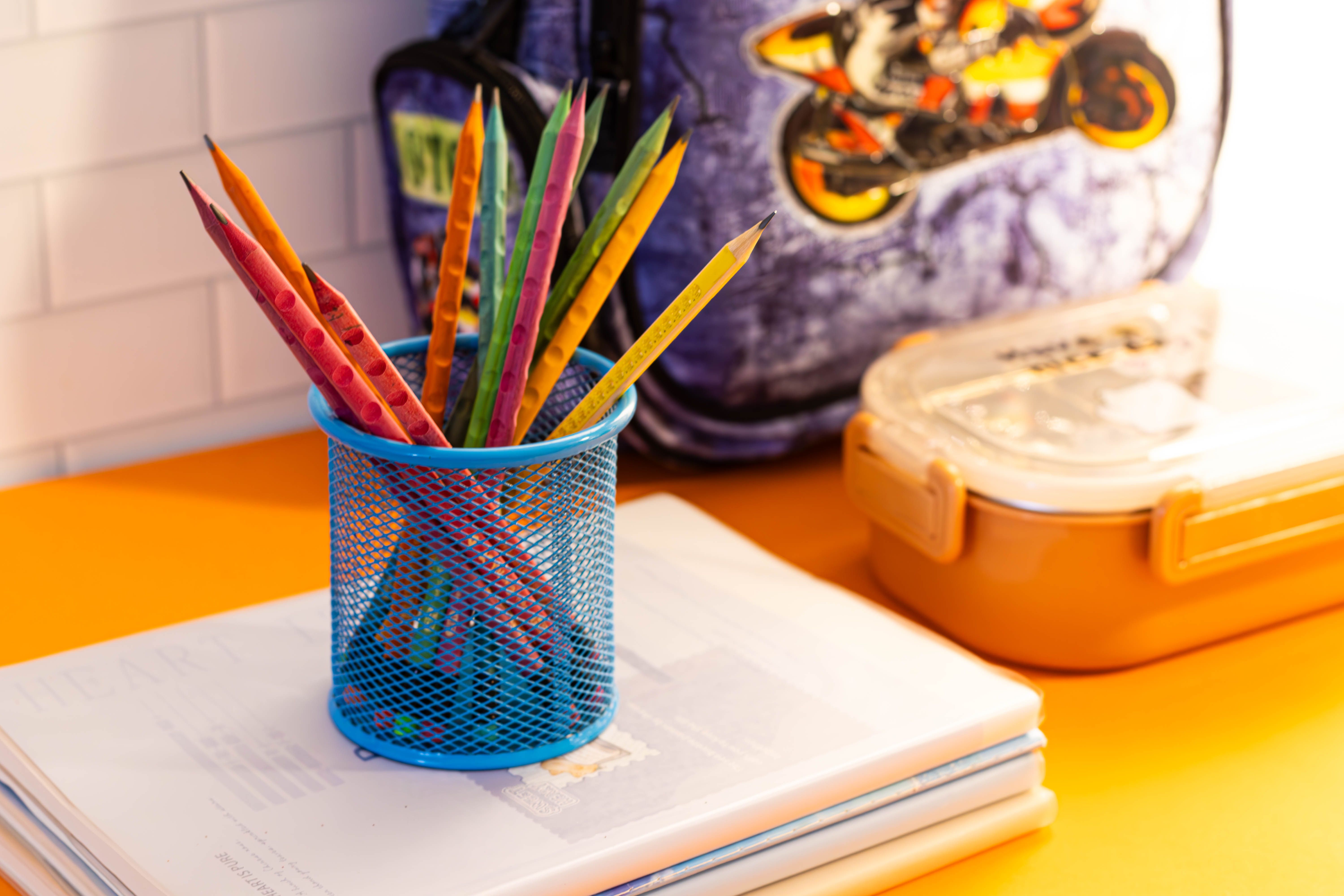 Colorful pencils, notebooks, backpack, lunchbox, and other back-to-school supplies on a desk. Colorful pencils, notebooks, backpack, lunchbox, and other back-to-school supplies on a desk.