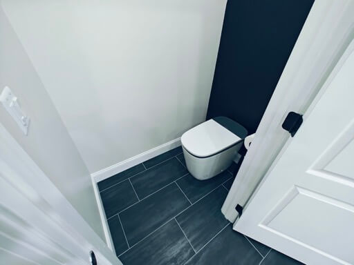 Matching second water closet with a navy accent wall and matte-black door hardware