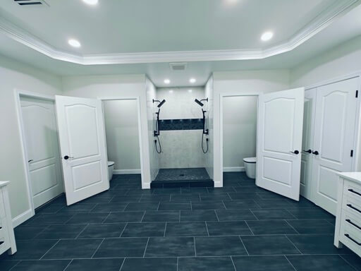 Curbless walk-in shower centered between two open water-closet doors in a Haymarket master bath