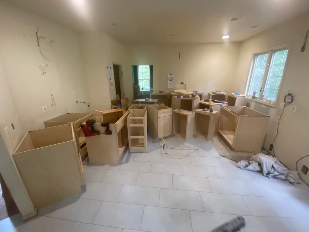 Kitchen mid-remodel in Alexandria with new tile floor and raw cabinet boxes being set to the homeowner's plan