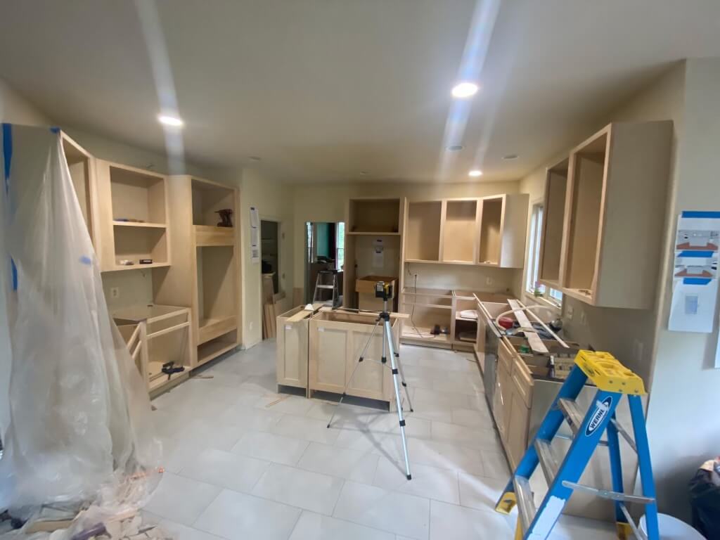 Kitchen remodel in progress with upper cabinets installed and the homeowner's rendering taped to the wall