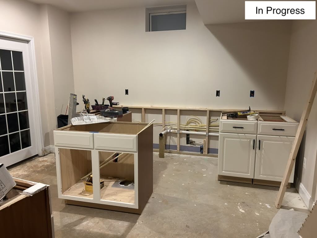 Basement wet bar in progress, with cabinet boxes set and rough plumbing and wiring run for the sink and appliances