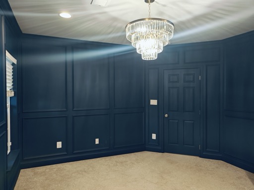 Basement bedroom with deep-navy custom picture-frame wall millwork and a tiered crystal chandelier