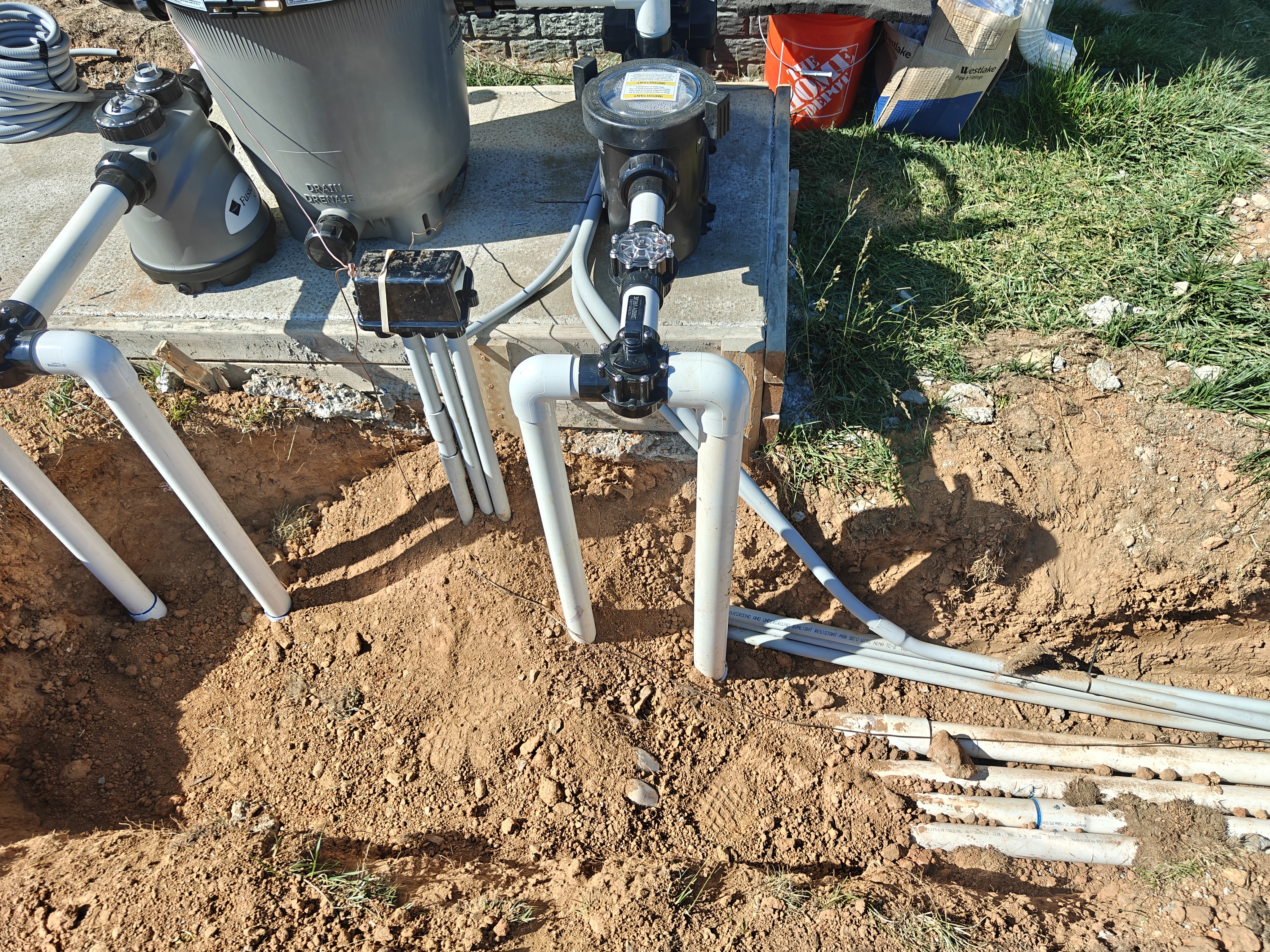 Pool plumbing risers coming out of the ground with the equipotential bonding connections tying the metal equipment together