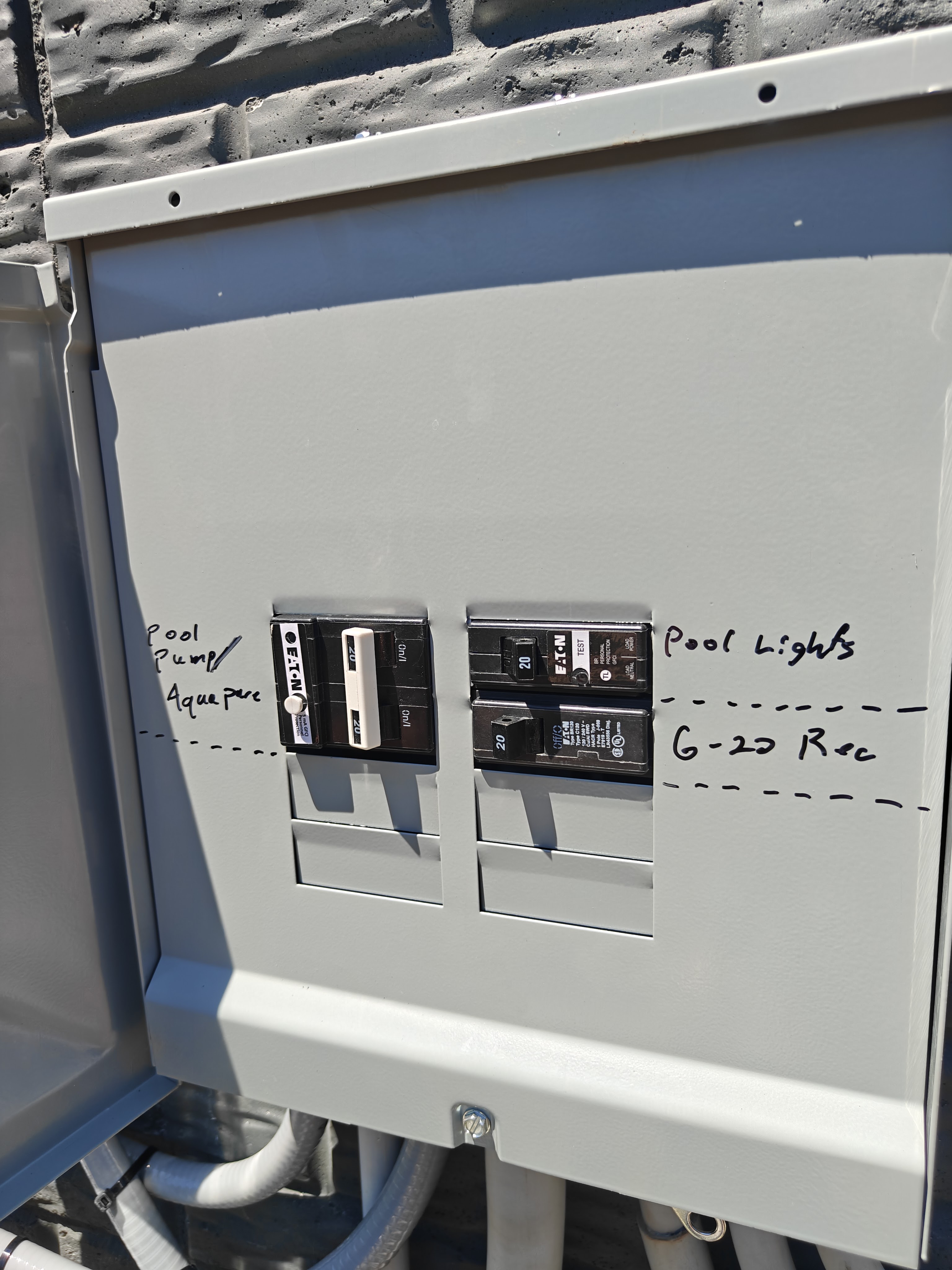 Open pool sub panel with handwritten labels showing GFCI-protected breakers for the pool pump and AquaPure, the pool lights, and the 6-20 receptacle