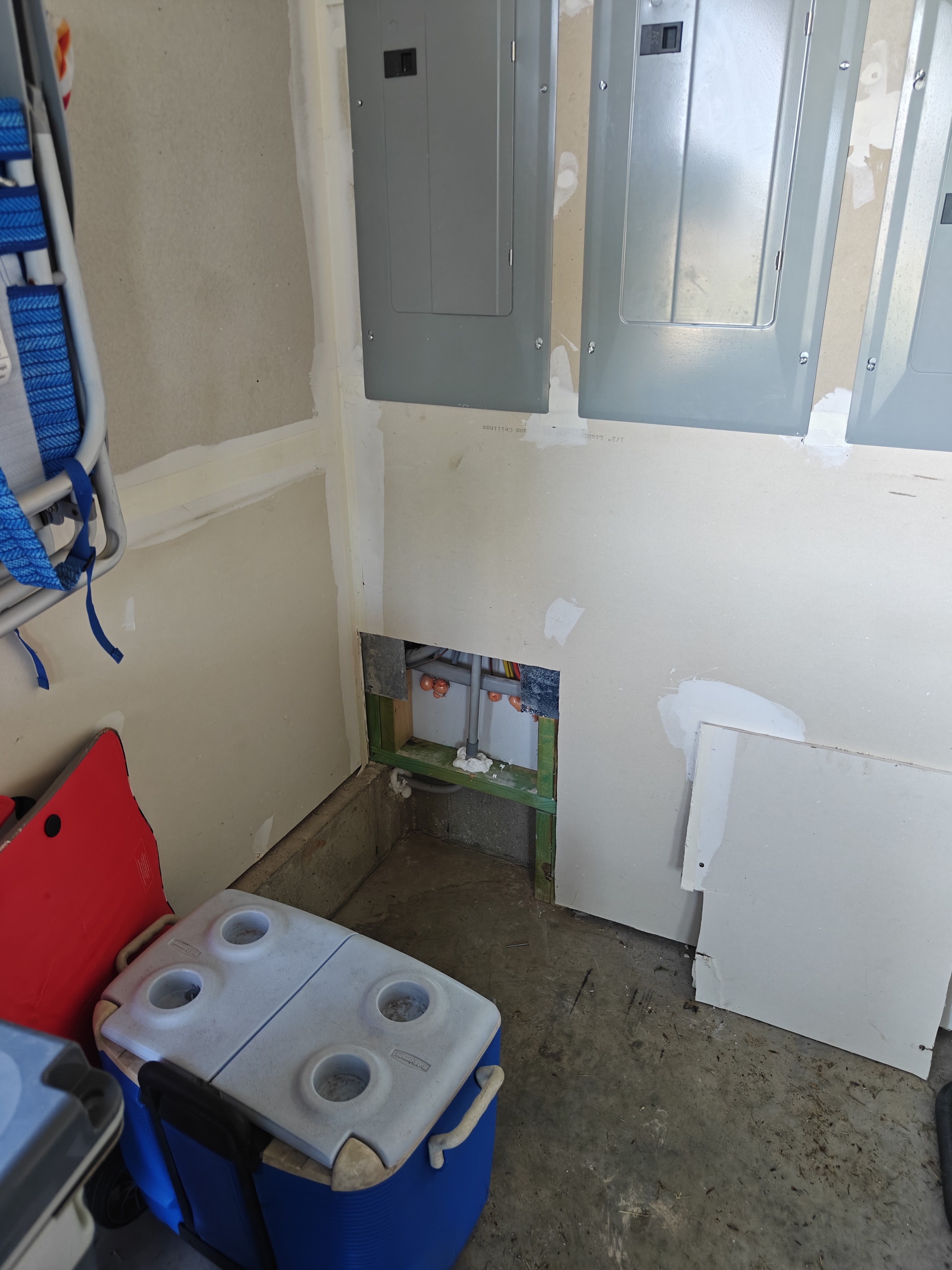 Indoor main electrical panels with a wall opening below where the new pool feed conduit was run out of the house