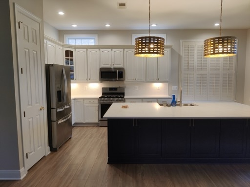 Finished kitchen remodel in Northern Virginia with a navy island, white cabinets, quartz counters, and pendant lighting