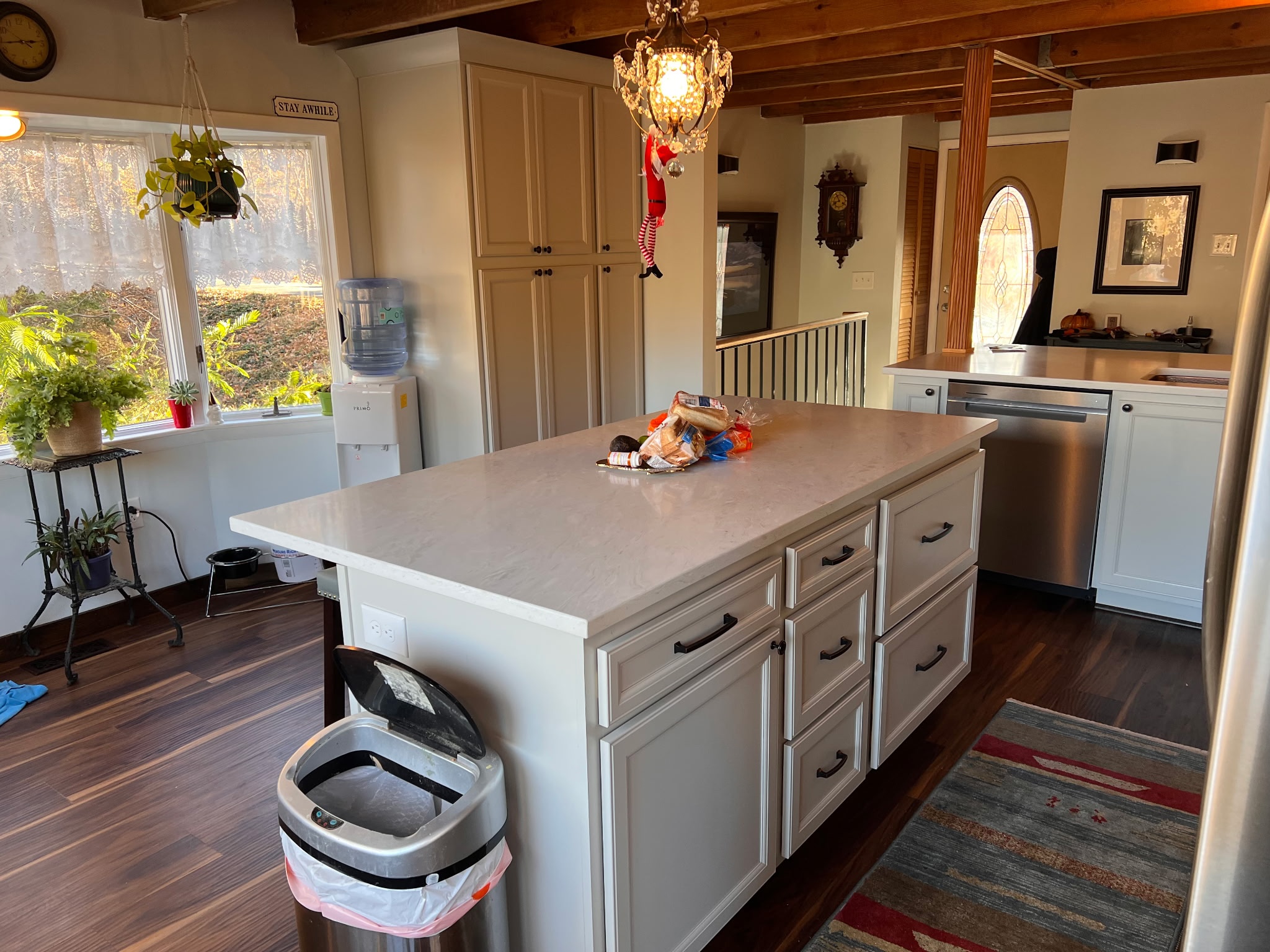 The finished kitchen island with a quartz counter and painted raised-panel cabinets, under the home's original exposed wood ceiling beams