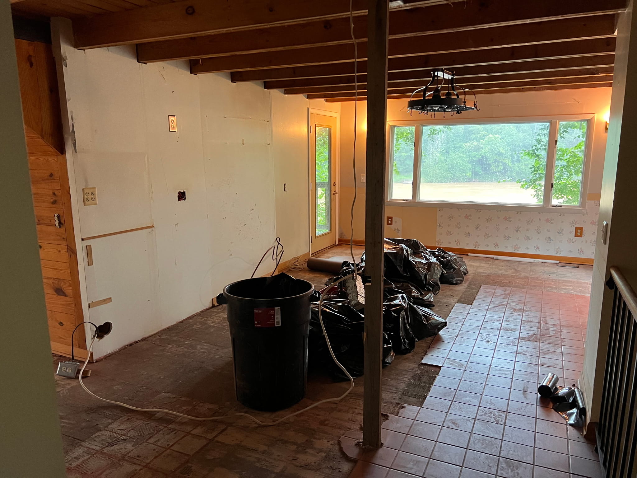 Kitchen stripped back during demolition, with cabinets and flooring removed and the original ceiling joists and beams exposed