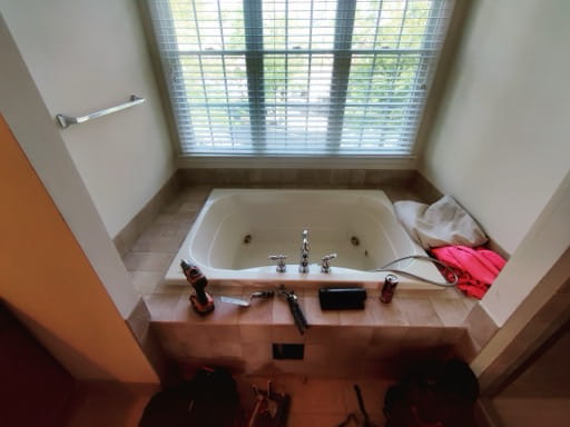 Before: a dated almond drop-in garden tub set into a large tiled deck under the window in a Prince William County master bathroom