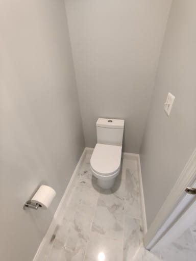 After: the finished water closet with a new white toilet, light walls, and marble-look tile carried through from the main bathroom