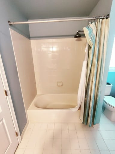 Before: a one-piece acrylic tub-and-shower insert with a curtain and white floor tile in a Prince William County hall bathroom