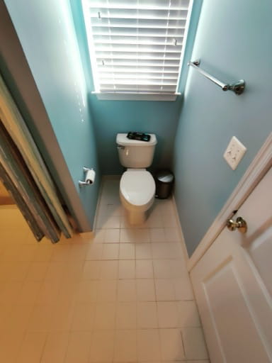 Before: the toilet nook with teal walls, an older toilet, and dated white floor tile in a Prince William County hall bathroom