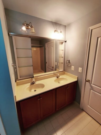 Before: a dated cherry bathroom vanity with a cultured-marble double sink top and a large frameless mirror in a Prince William County hall bath