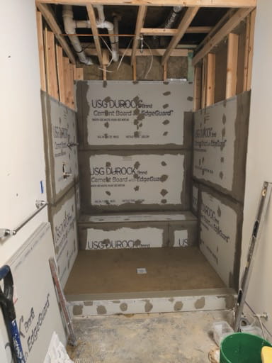 The basement shower during construction, framed and set in cement board with a mortared shower pan and rough-in plumbing overhead