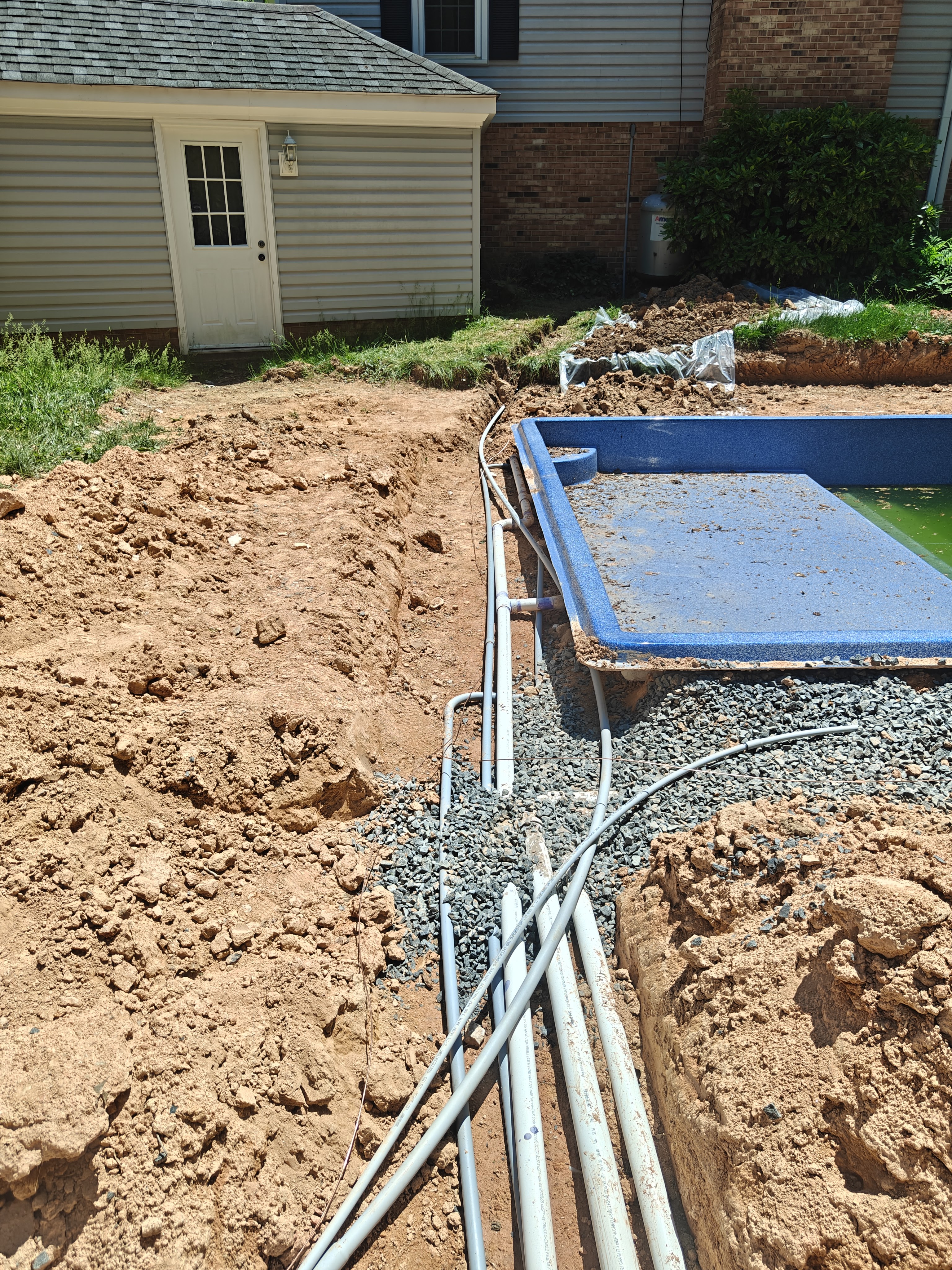 Conduit and bond wire reaching the new fiberglass pool shell at the far end of the trench
