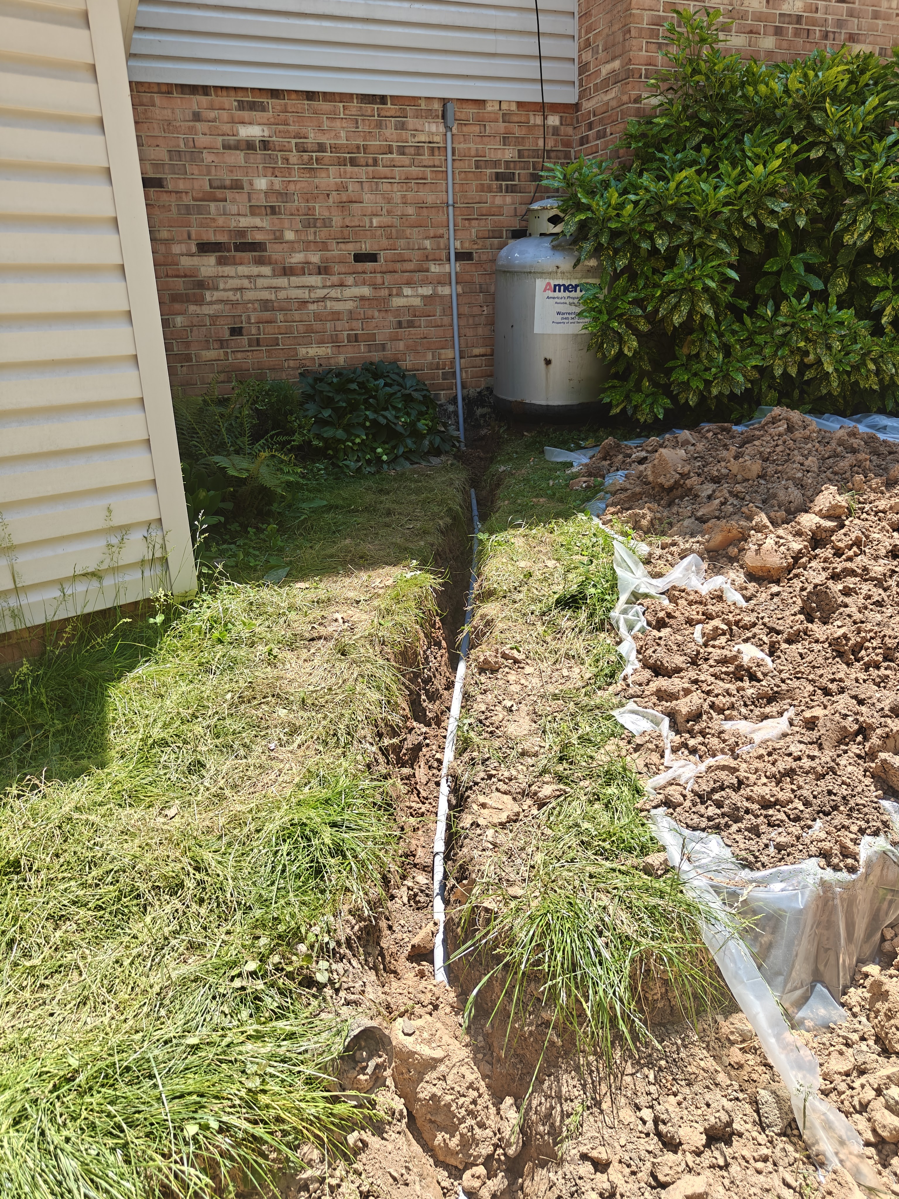 One-inch conduit run out of the basement bulkhead and down into a trench beside the brick house in Manassas
