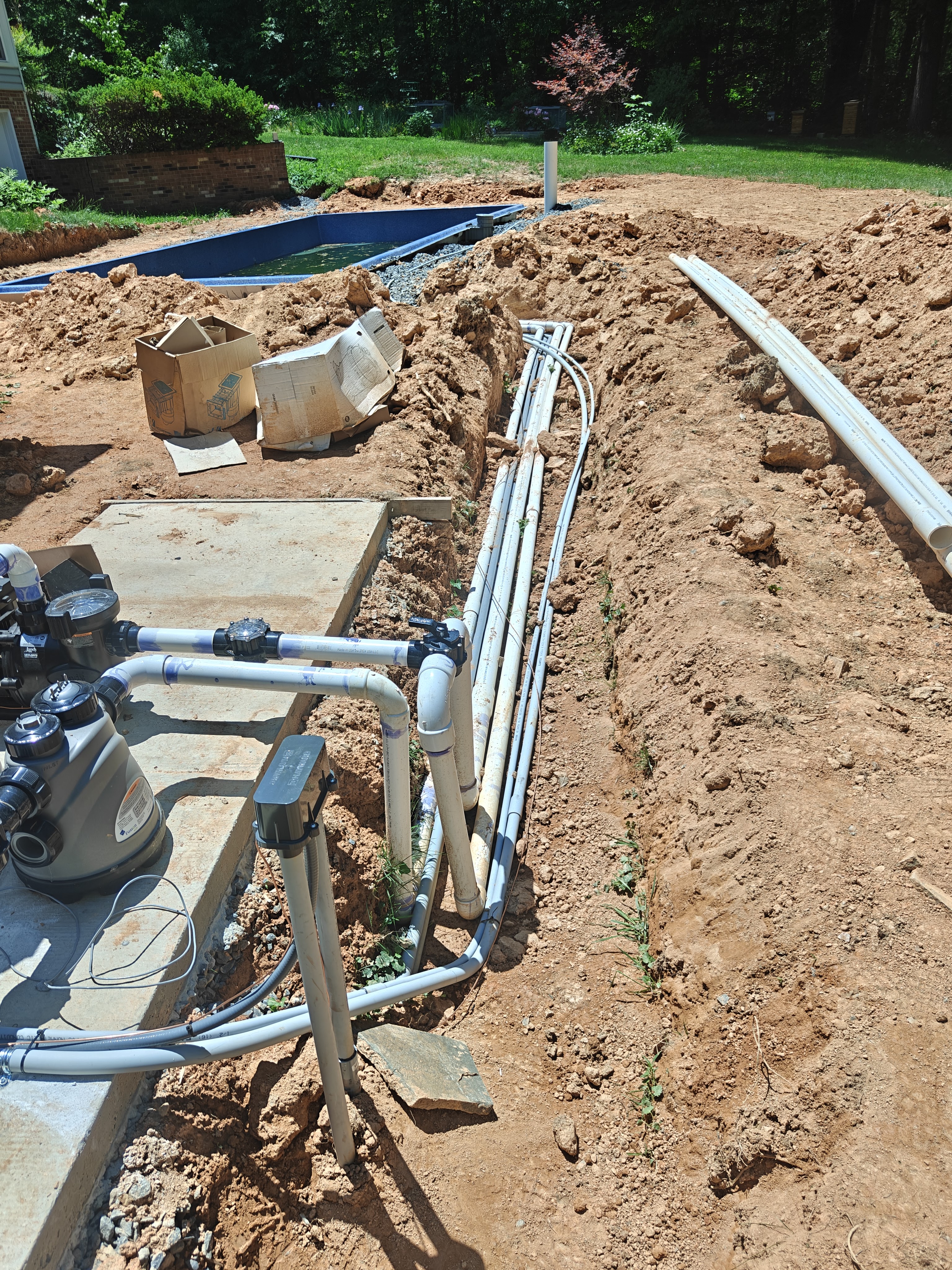 Trenched conduit and bonding wire running from the pool equipment pad toward the new pool