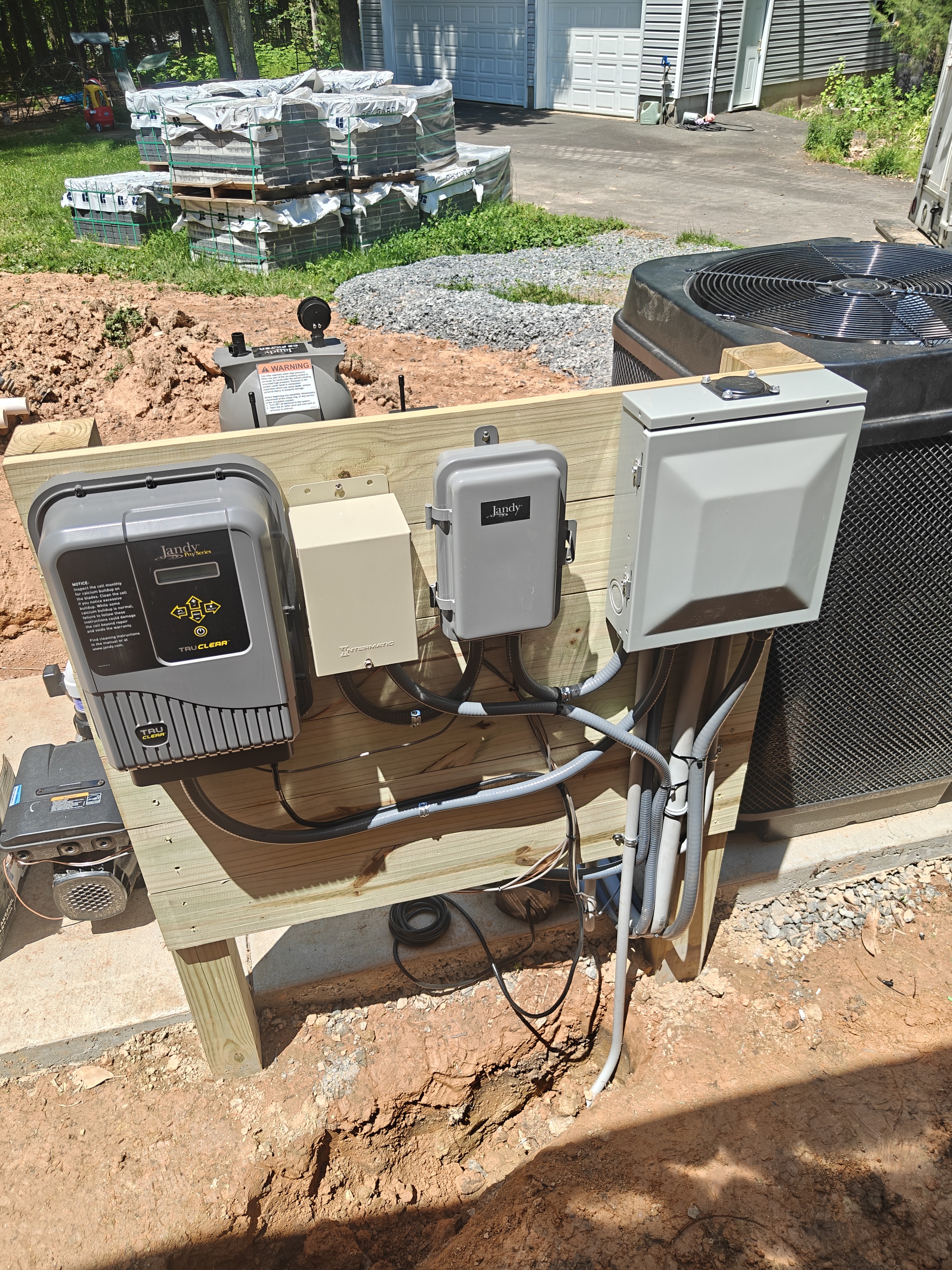 Custom 4x4-post and 1x6-board equipment rack mounting a pool sub panel, Jandy disconnect, transformer, and TruClear salt cell with flex conduit runs