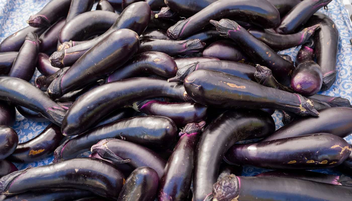 Glossy eggplants stacked on a market table