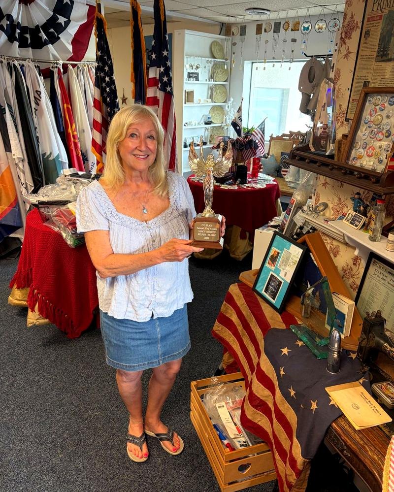 Karen Bush, founder of Flag & Banner Co., holding the Betsy Ross Award in the shop