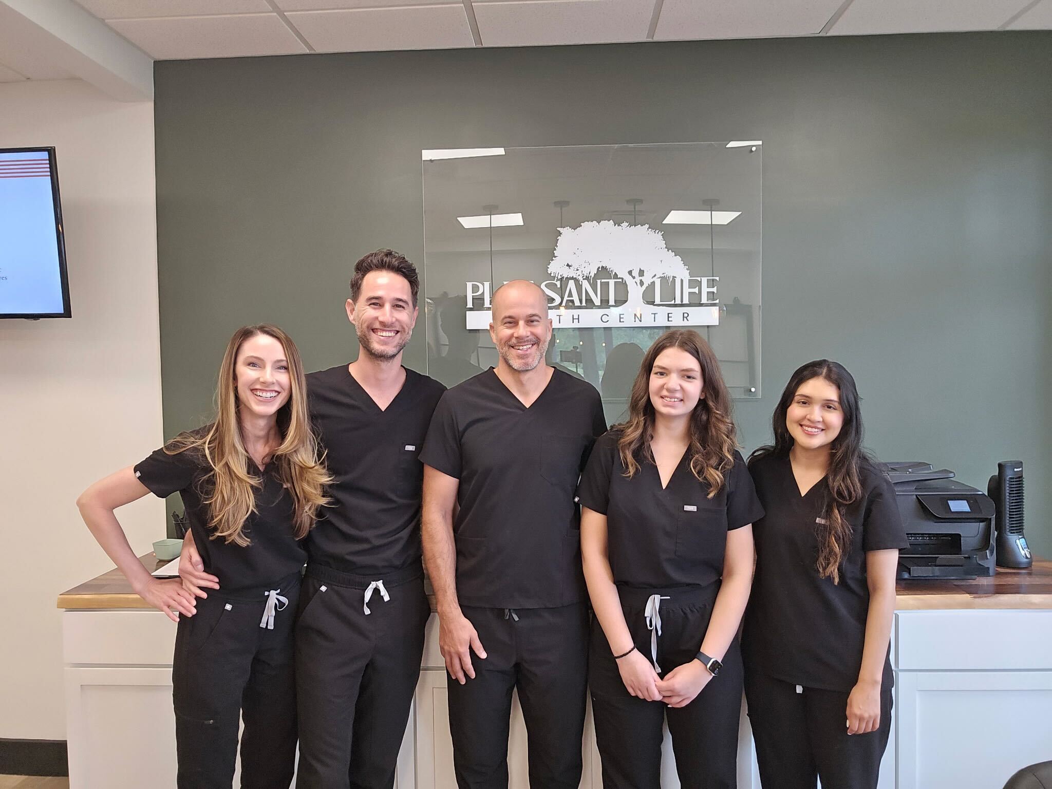 The team at Pleasant Life Health Center in front of the clinic sign