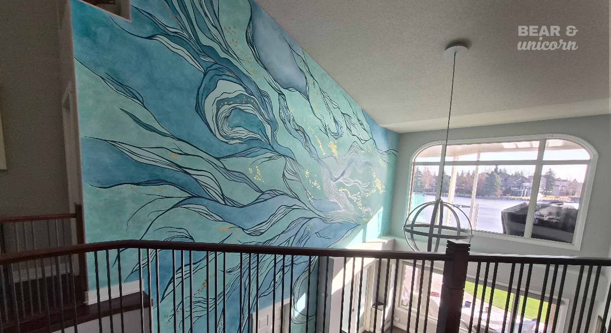 The finished abstract piece, "Shimmering Shallows," highlighting how the natural light reflecting from the lake outside plays on the hand-painted gold detailing of the installation. The finished abstract piece, "Shimmering Shallows," highlighting how the natural light reflecting from the lake outside plays on the hand-painted gold detailing of the installation.