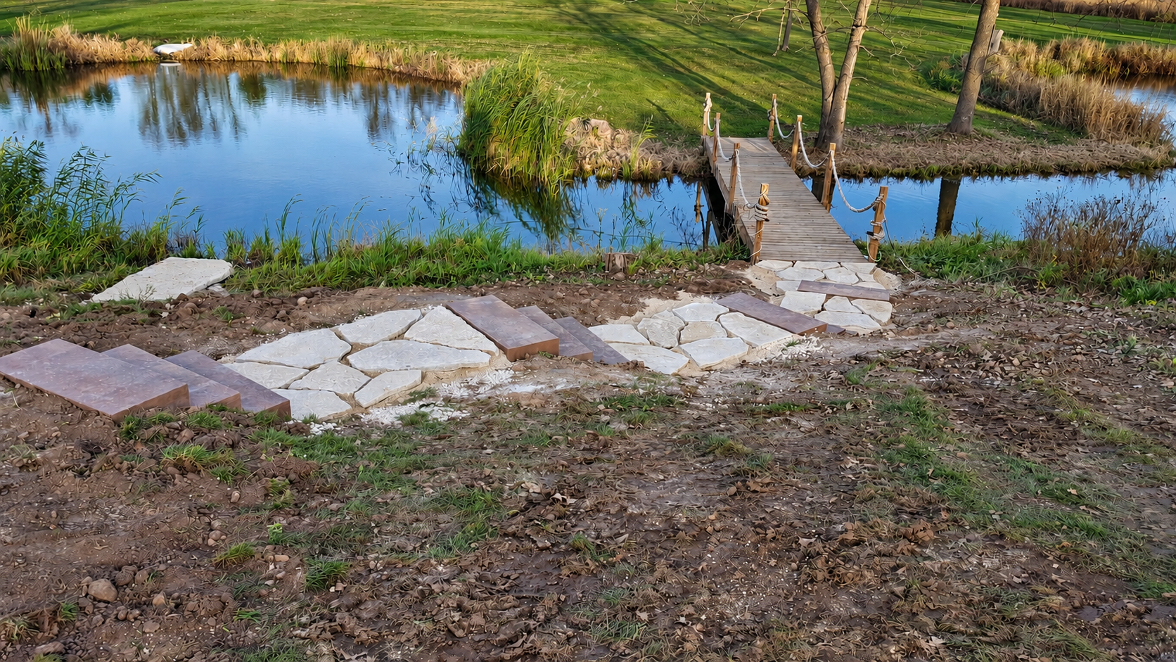 Stone steps leading to a wooden bridge over a pond, a MasterPlan Landscapes, LLC project