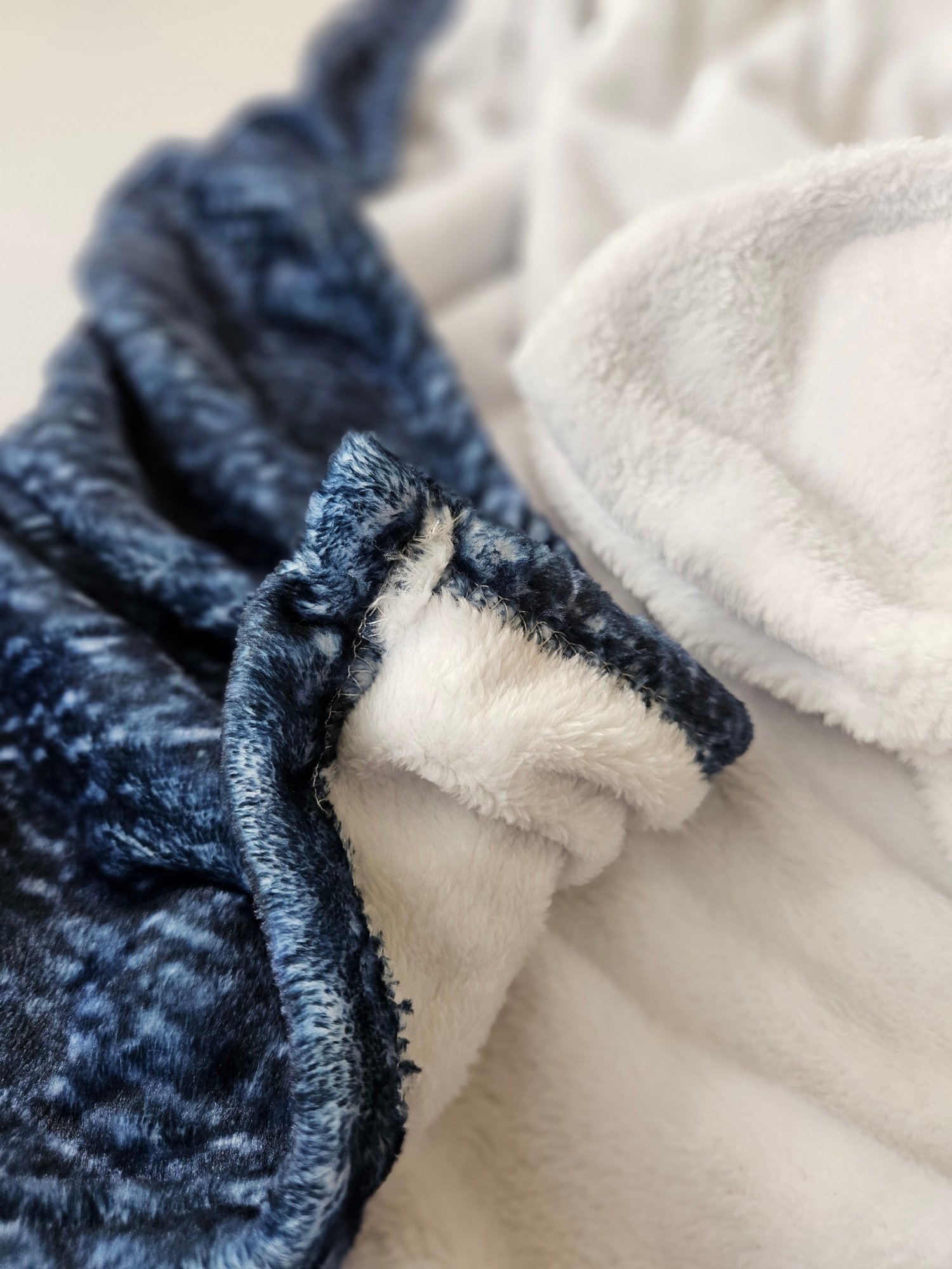 Close-up of navy blue and white fleece blankets stacked together